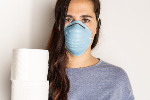 Frau mit Mundschutz und Toilettenpapier